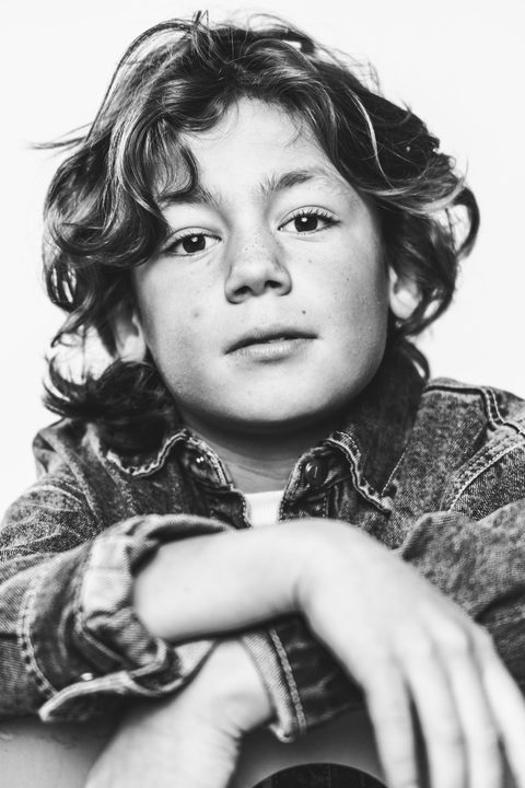 Zwart-witportret van een jongen met krullen in een spijkerjack