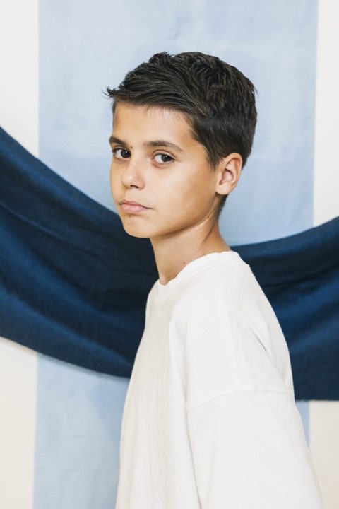 Jongen in wit shirt voor een blauwe doek