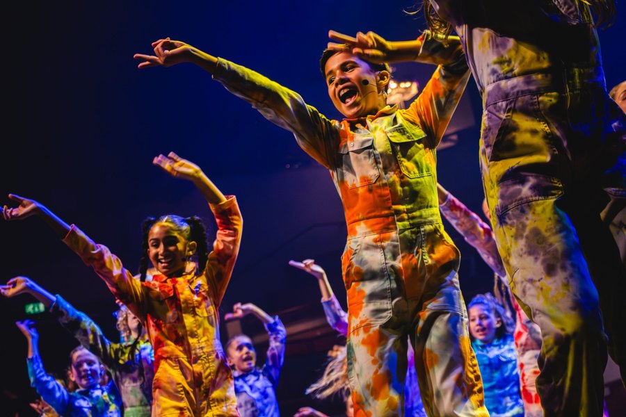 Kinderen dansen en zingen op het podium tijdens een concert van Kinderen voor Kinderen