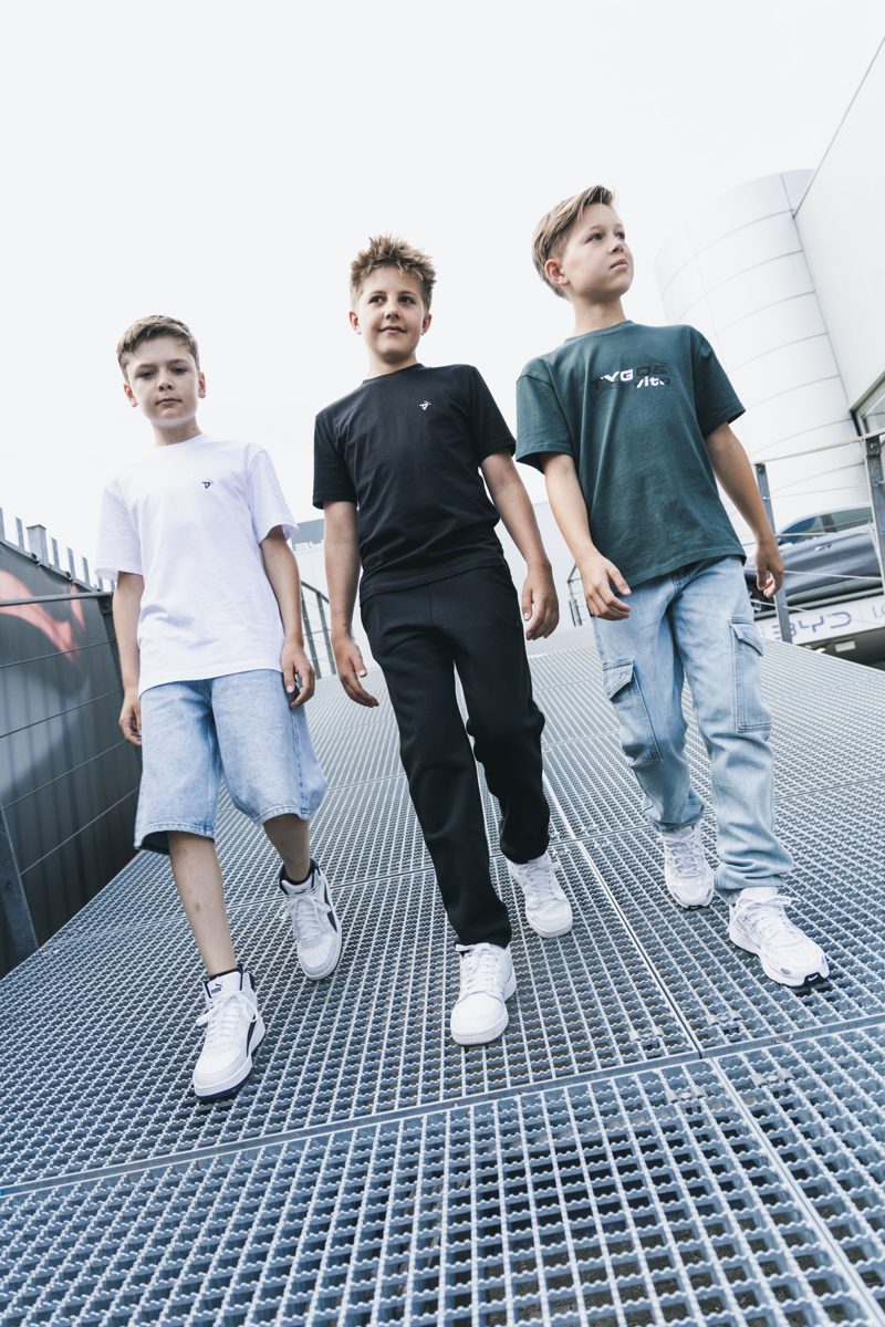 Drie jongens lopen over een metalen trap in kleding van Tygo & Vito