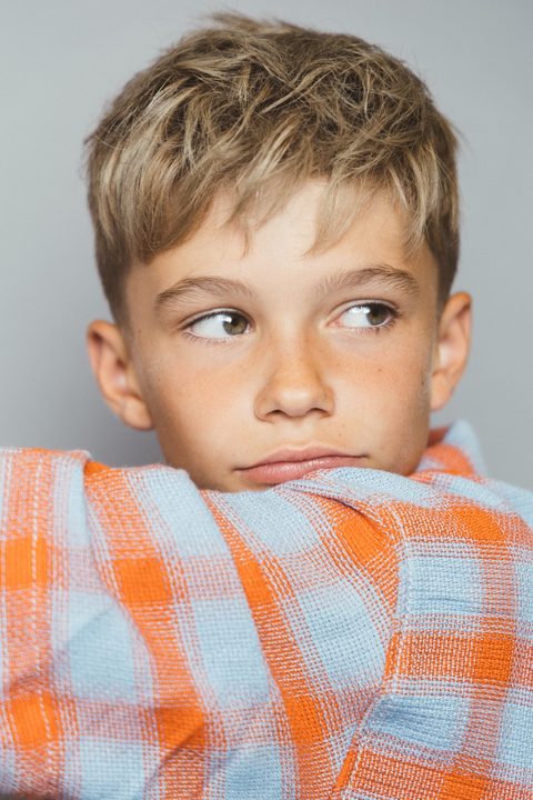Jongen in oranje geruit overhemd kijkt opzij