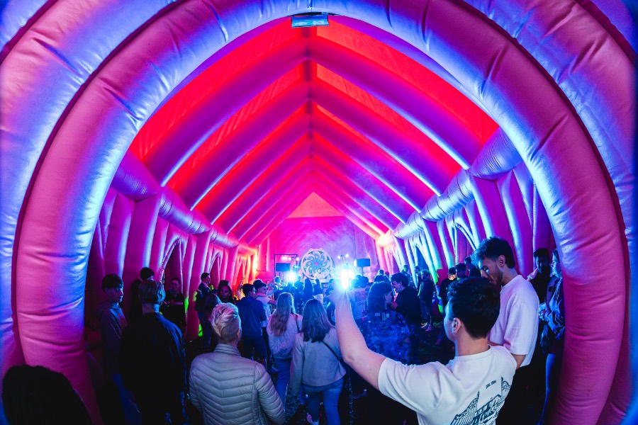 Publiek onder paarse lichtbogen op het festivalterrein