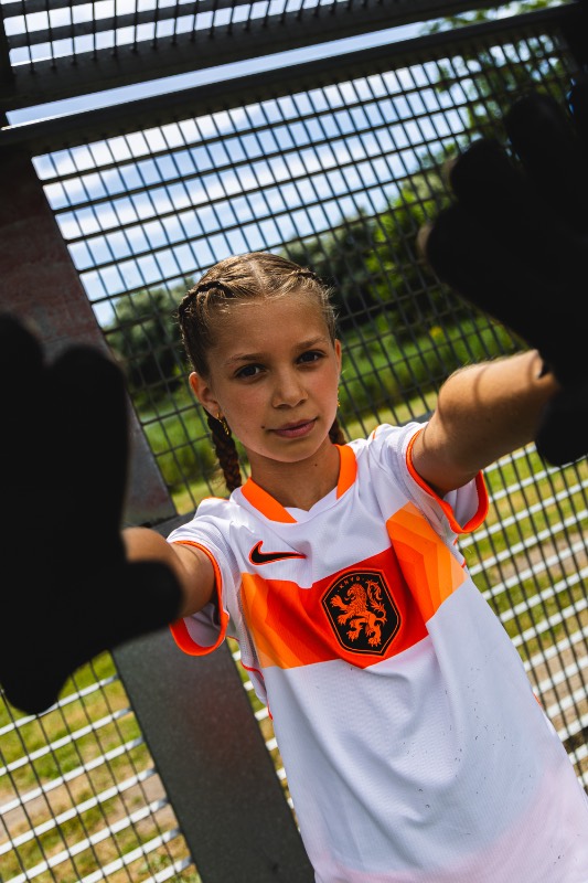 Kind in voetbaltenue op de bal langs het veld